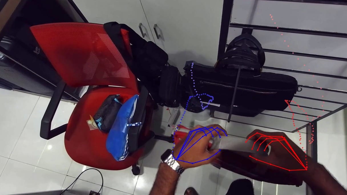 First-person video frame with blue and red joint lines tracking both hands, from Humyn Labs robot training footage